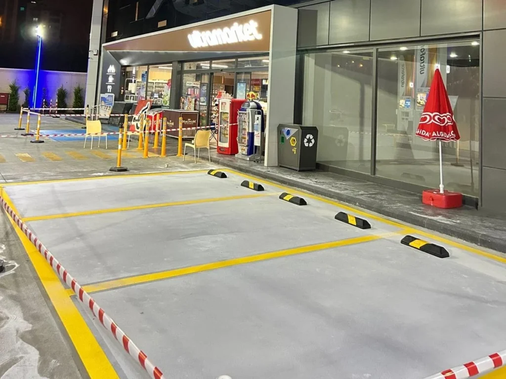 Akaryakıt istasyonu otoparkında sarı park çizgileri ve siyah sarı araç stoperleri