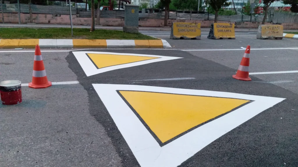 Asfalt yola uygulanan sarı ve beyaz üçgen trafik kasis uyarı sembolleri