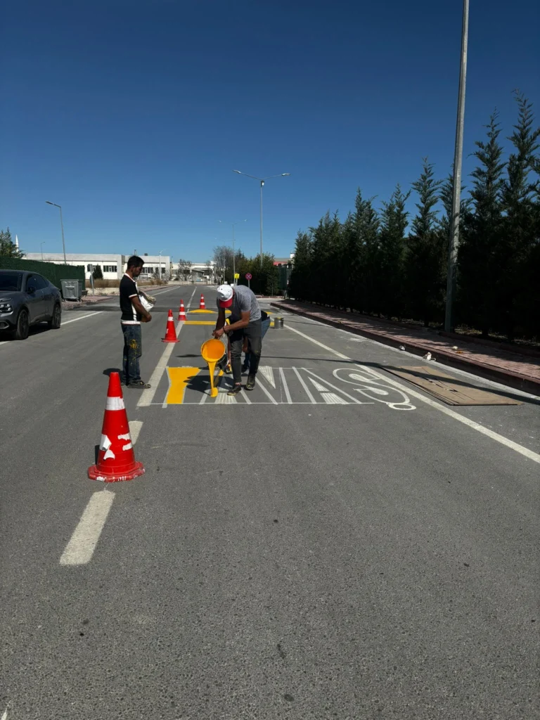 Asfalt yola çift komponentli sarı boyayla YAVAŞ yazısı uygulanması