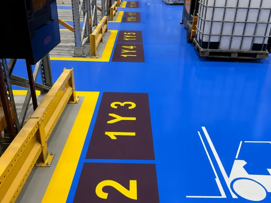 Fabrika deposunda mavi zemin, sarı güvenlik çizgileri, forklift sembolü ve alan numaraları