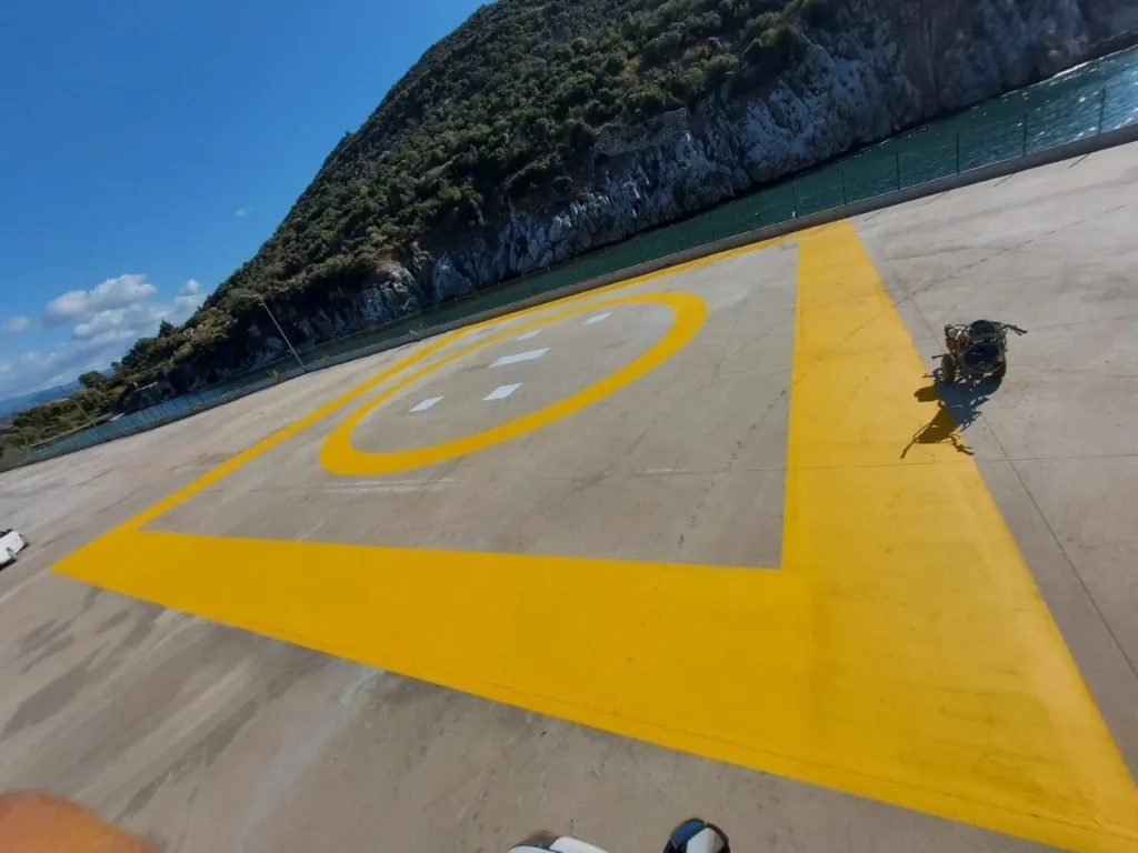 Beton zemine uygulanan sarı helikopter pisti sınır çizgileri ve iniş alanı işareti