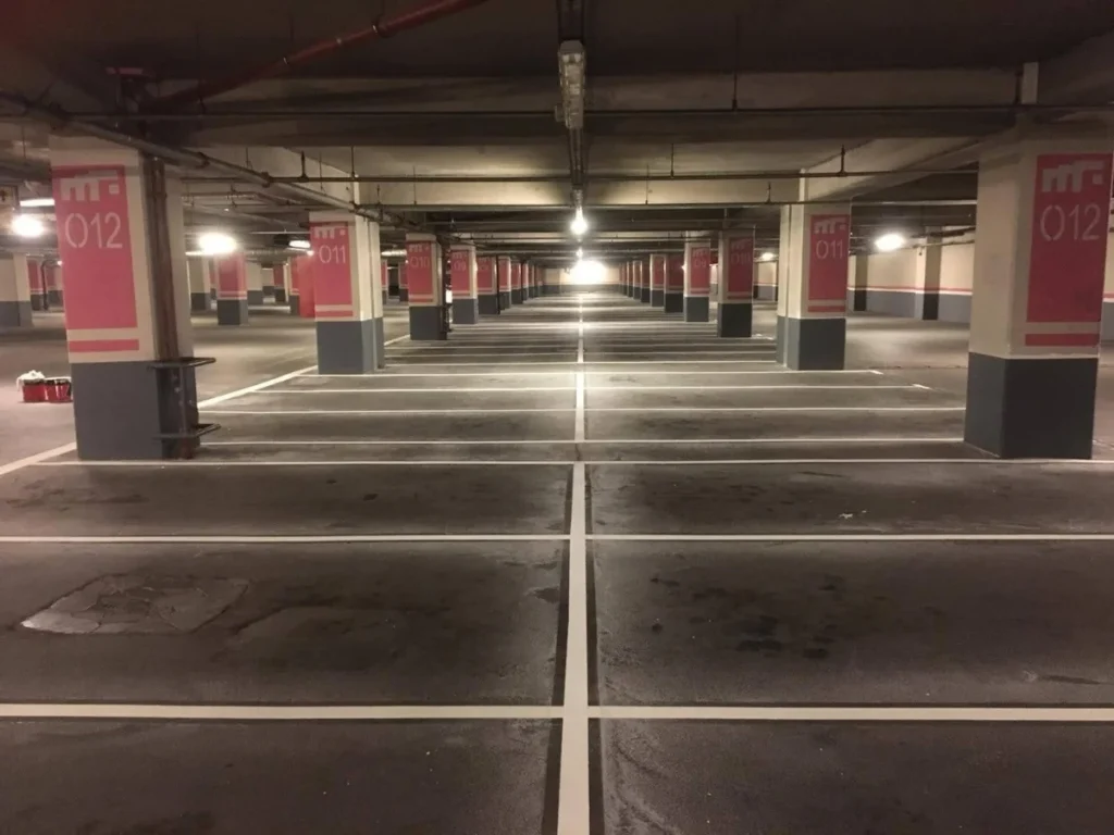 Kapalı otoparkta beyaz park yeri çizgileri ve numaralandırılmış kolonlar