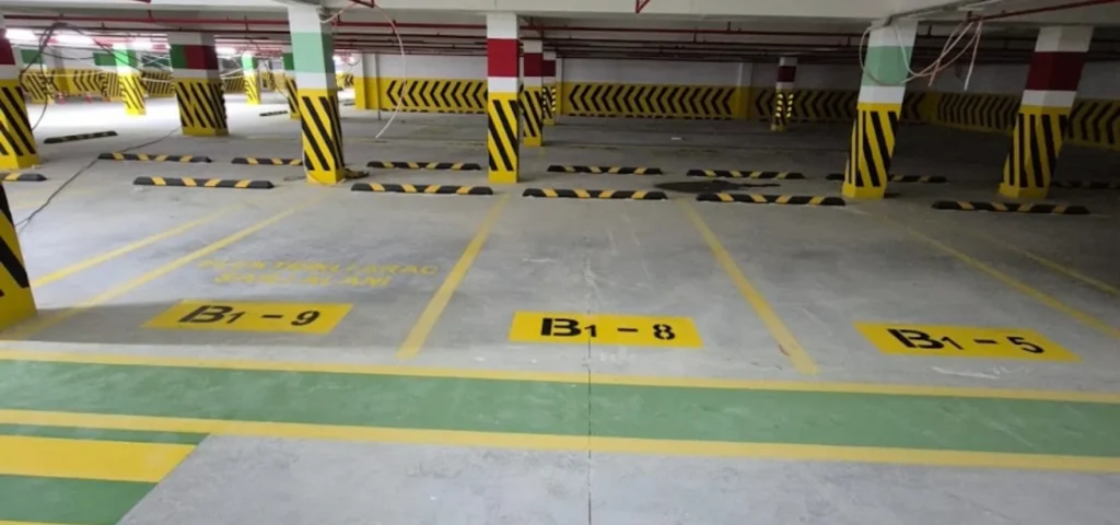 Kapalı otoparkta numaralandırılmış park yerleri, sarı çizgiler ve renkli zemin yönlendirmeleri