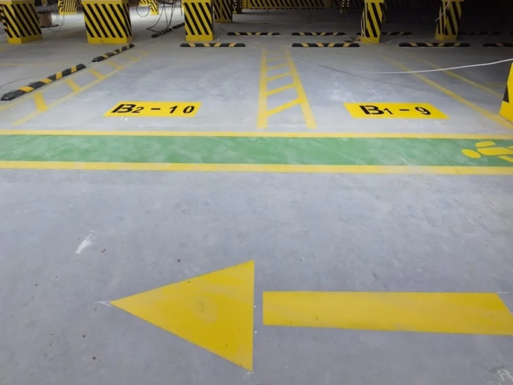 Kapalı otoparkta park yeri belirleme numaraları, sarı yön oku ve yeşil yaya yolu uygulaması