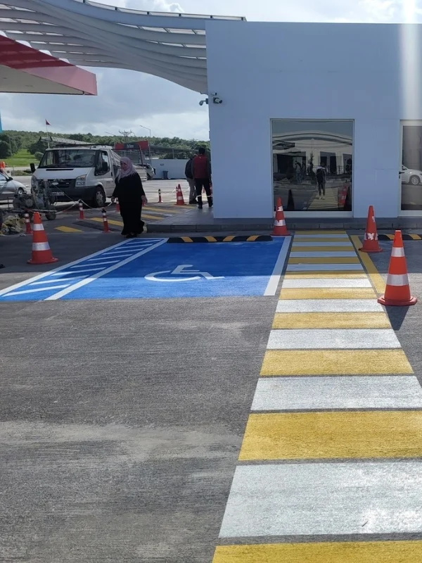 Akaryakıt istasyonunda engelli park alanı ve sarı-beyaz yaya geçidi