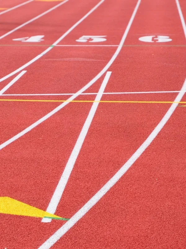Kırmızı atletizm koşu pistine uygulanan beyaz başlangıç çizgileri ve kulvar numaraları