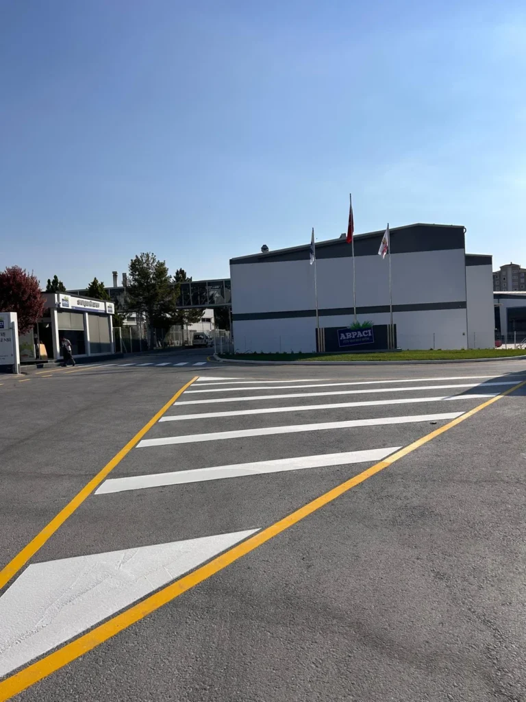 Asfalt yol ayrımında çift kompenantlı beyaz boyayla uygulanan tarama alanı, yönlendirme işareti ve sarı çizgiler