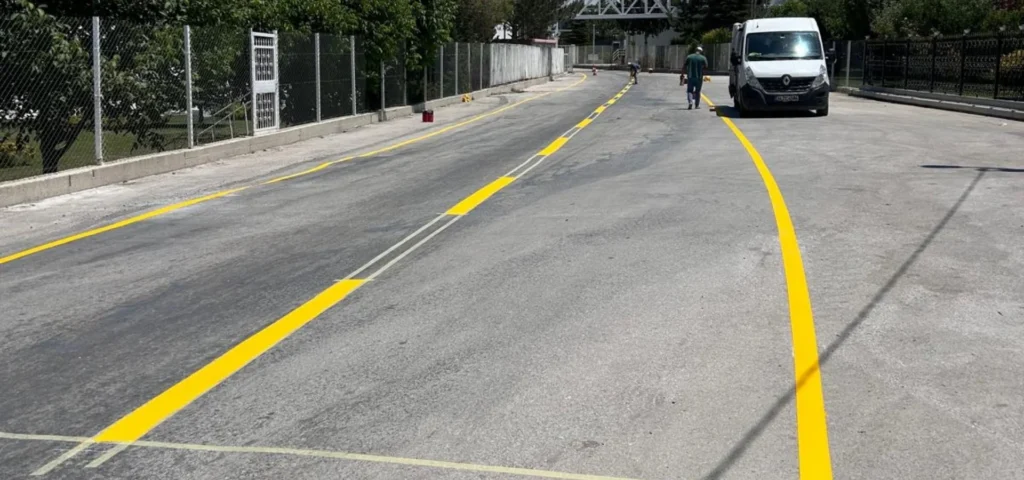 Tesis yoluna çift kompenantlı sarı boya ile uygulanan şerit ve kenar çizgileri