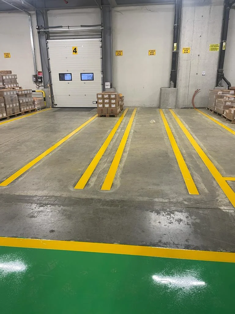 Fabrika deposunda 4 numaralı sevk kapısı önünde sarı çizgilerle ayrılan palet hazırlama alanları