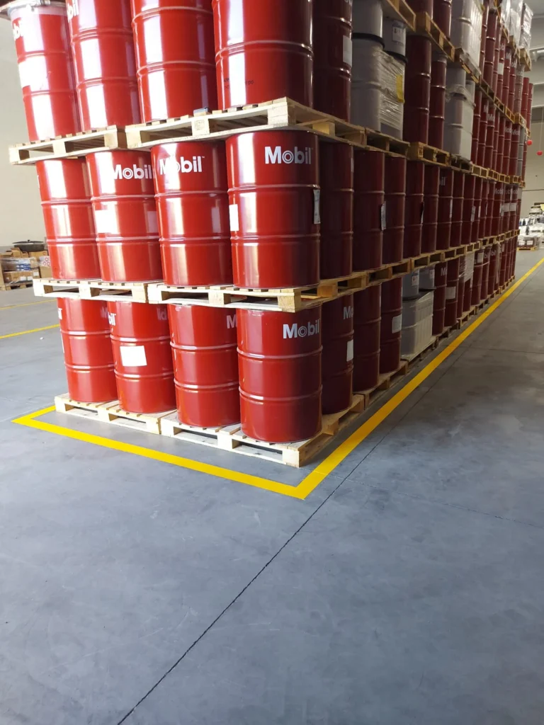 Depoda paletler üzerinde istiflenen varillerin çevresine uygulanan sarı stok alanı sınır çizgisi