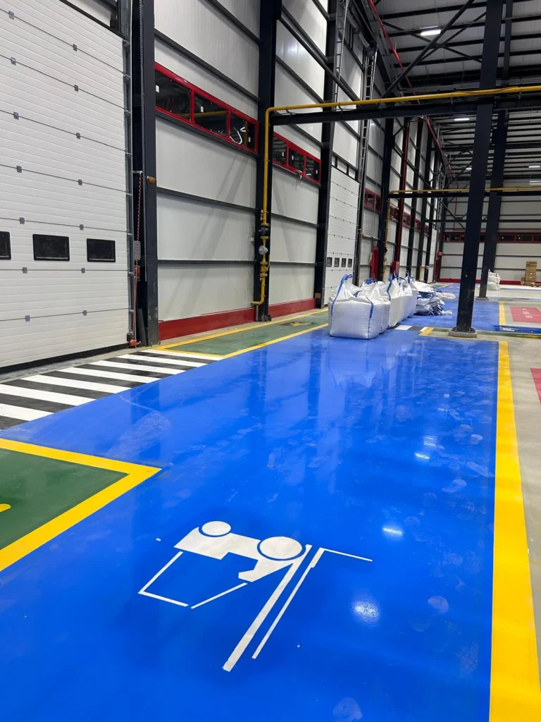 Depo kapıları önünde mavi forklift yolu, yeşil yaya yolu ve siyah beyaz geçiş boya ve çizgileri