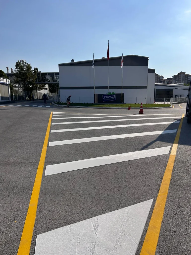 Fabrika içi asfalt yola çift kompenantlı beyaz boyayla uygulanan ofset tarama ve sarı sınır çizgileri