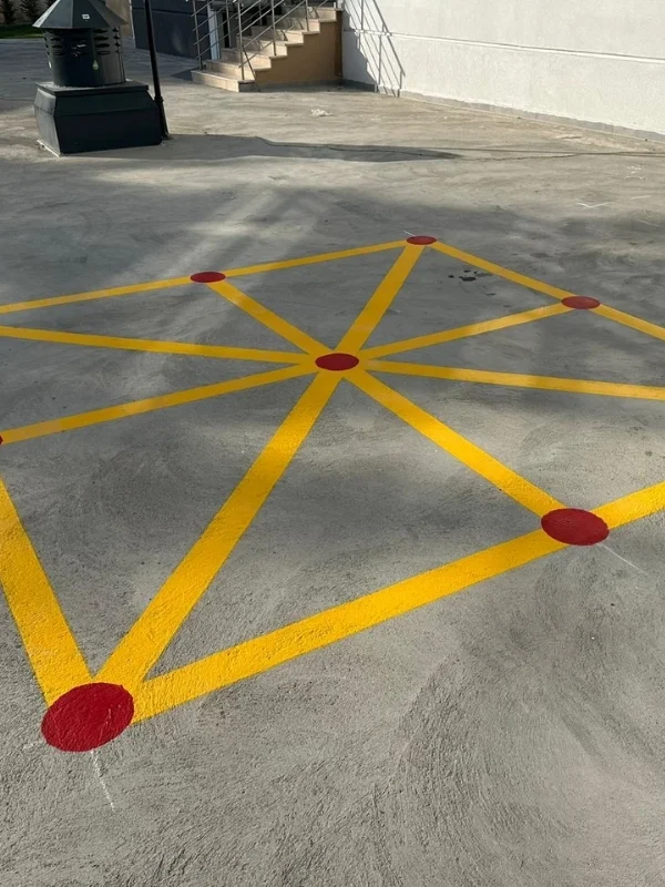 Beton zemine sarı çizgiler ve kırmızı noktalarla uygulanan geometrik hareket oyunu