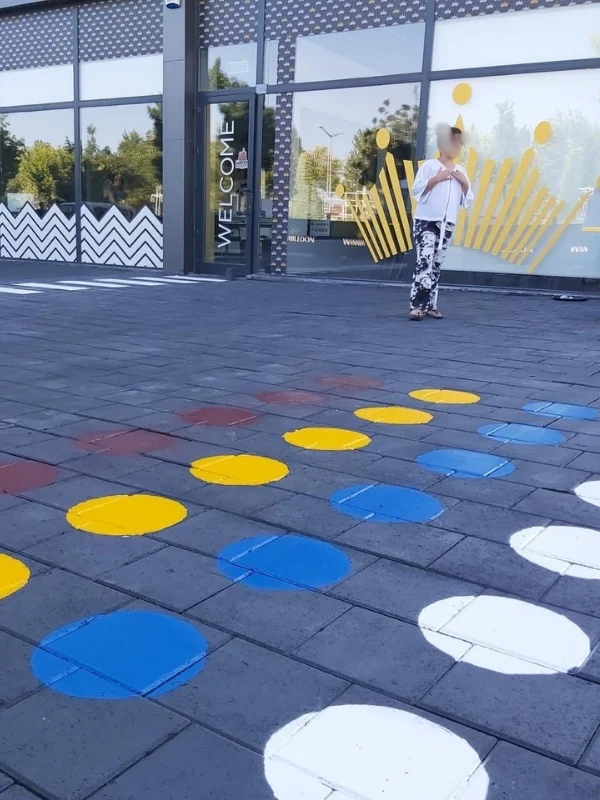 Okul bahçesi zeminine sarı, mavi, beyaz ve kırmızı dairelerle uygulanan adım parkuru