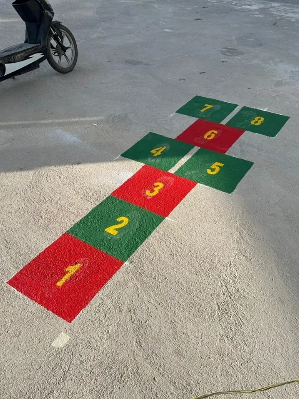 Okul bahçesi beton zeminine kırmızı ve yeşil renklerle uygulanan sekiz bölümlü seksek oyunu
