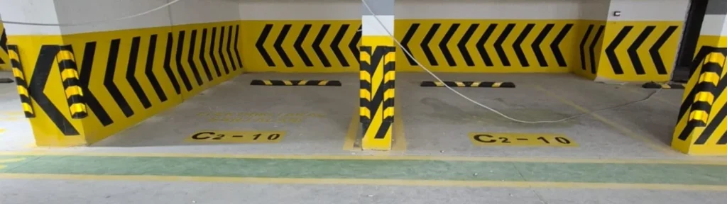 Kapalı otoparkta kolon ve duvarlara uygulanan sarı-siyah çavuş tarama ile park yeri numaralandırması