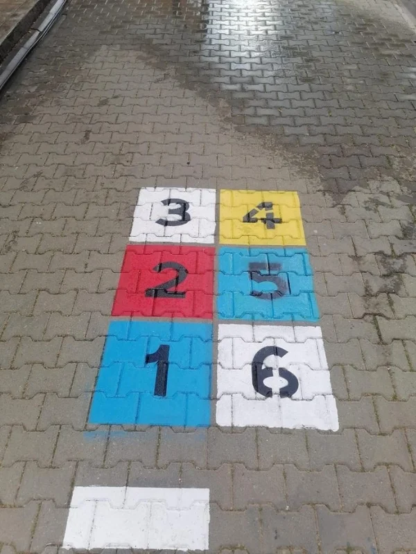 Okul bahçesindeki kilitli taşlara boyanan renkli ve rakamlı altı bölümlü seksek oyunu