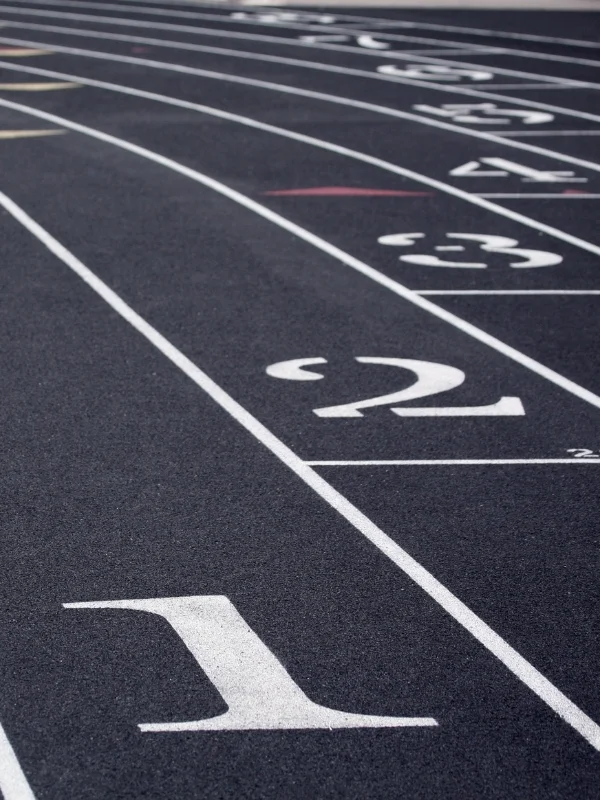 Siyah atletizm pisti üzerinde beyaz kulvar çizgileri ve büyük kulvar numaraları