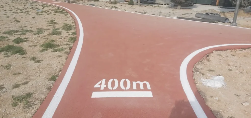 Spor alanındaki kırmızı koşu yoluna uygulanan beyaz sınır çizgileri ve 400 metre mesafe işareti