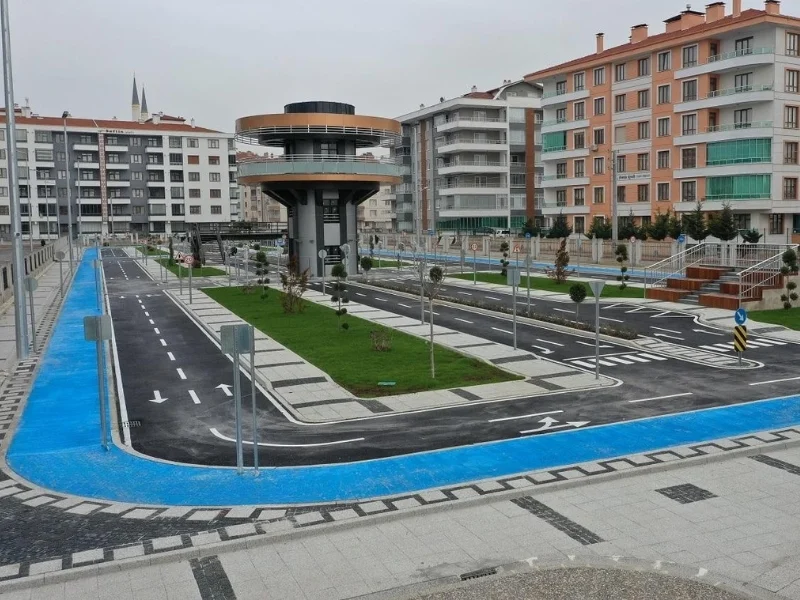 Trafik eğitim pistini çevreleyen mavi bisiklet yolu ile kavşak ve yön çizgileri