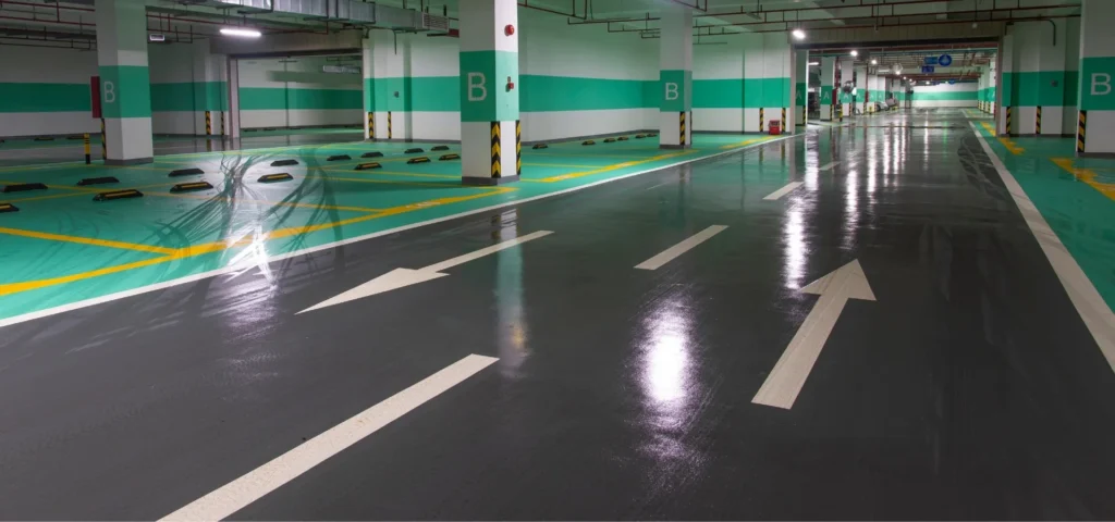 Kapalı otoparkta epoksi boya üzerine uygulanan beyaz şerit çizgileri, yön okları ve sarı park çizgileri